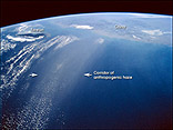 This photograph, taken from the Space Shuttle on 4 March 1996, shows a coherent corridor of anthropogenic haze (between arrows), probably a mixture of industrial air pollution, dust, and smoke, in the left half of the view against the dark background of the East China Sea.  The corridor is approximately 200 Km wide and probably much more than 600 Km long (the visible length over the sea). The transport of smog from East Asia has been confirmed in measurements of the atmosphere over North America.